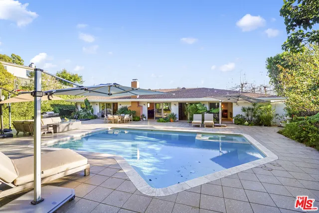 a view of a swimming pool with lawn chairs under an umbrella