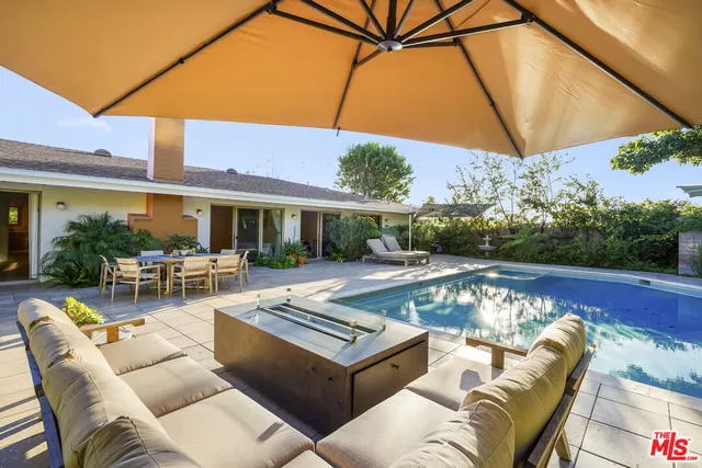 a view of a patio with couches table and chairs under an umbrella