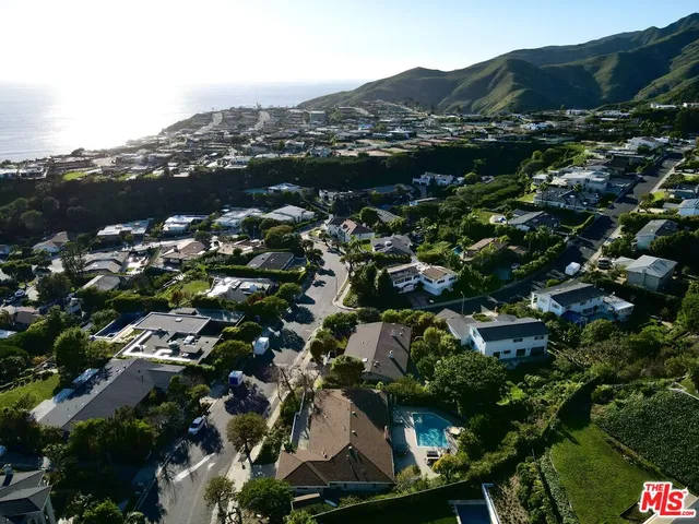 an aerial view of residential houses with outdoor space and trees