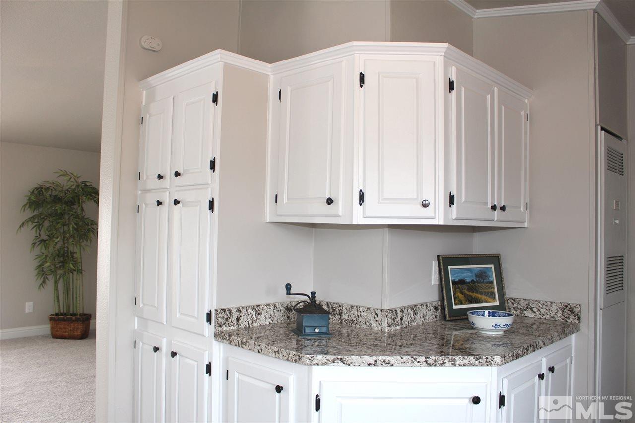5189 Coggins Road Reno, NV 89506 - Photo 12 of 33 a kitchen with granite countertop a white refrigerator oven a sink and white cabinets