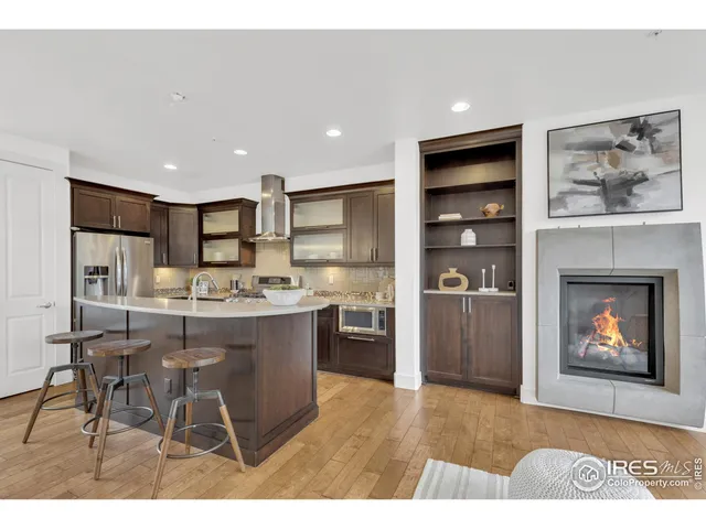 a kitchen with stainless steel appliances granite countertop a refrigerator a stove a sink and a dining table with wooden floor