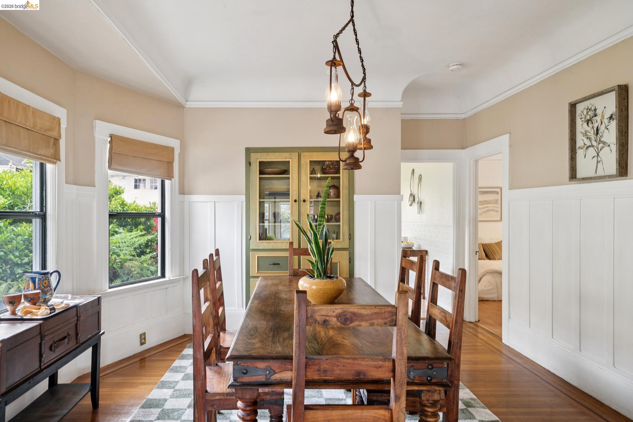 892 Laurel Street Alameda, CA 94501 - Photo 12 of 45 Formal dining space featuring hardwood flooring, white board and batten wall detailing, a built-in display cabinet, a decorative chandelier, and natural light from two windows