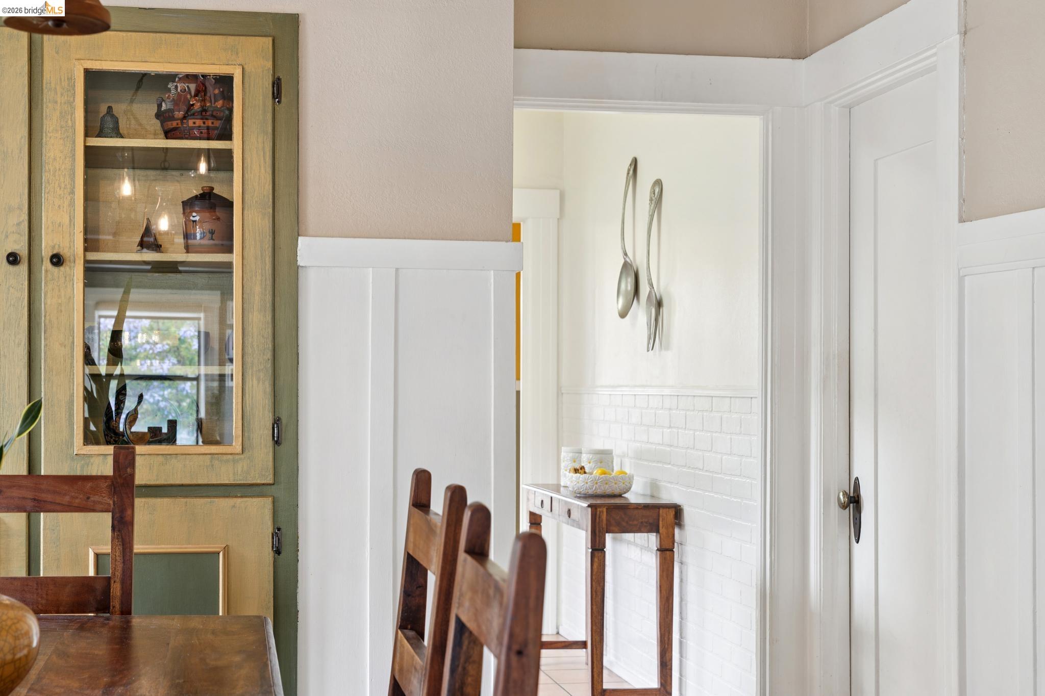 892 Laurel Street Alameda, CA 94501 - Photo 15 of 45 Built-in cabinetry with glass-front display shelves, white board and batten wainscoting, and a doorway featuring a white subway tile wainscoting