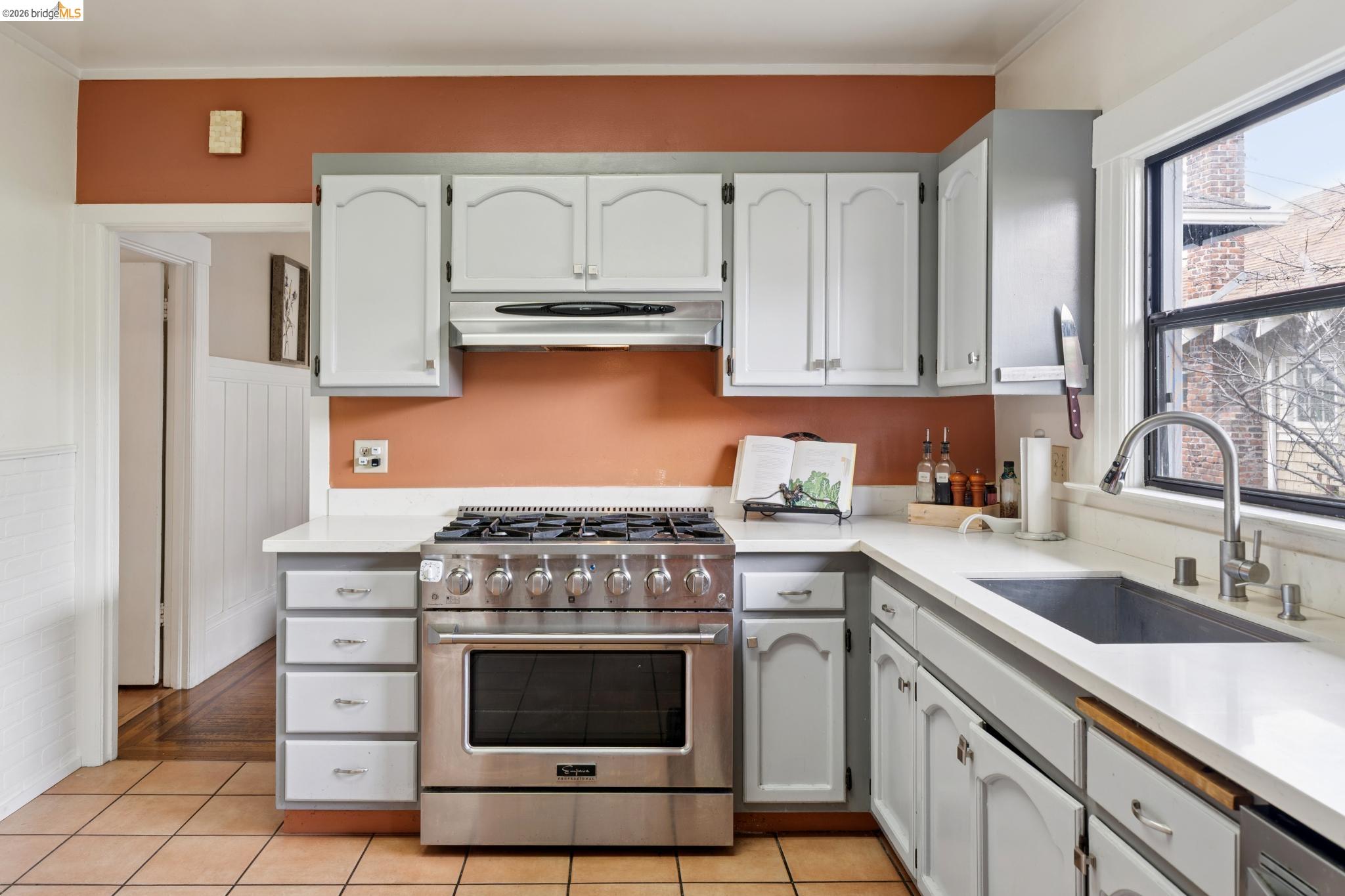 892 Laurel Street Alameda, CA 94501 - Photo 20 of 45 Kitchen featuring a stainless steel range with a ventilation hood, white cabinetry, light-toned countertops, a stainless steel sink with a pull-down faucet, and terracotta-style floor tiling