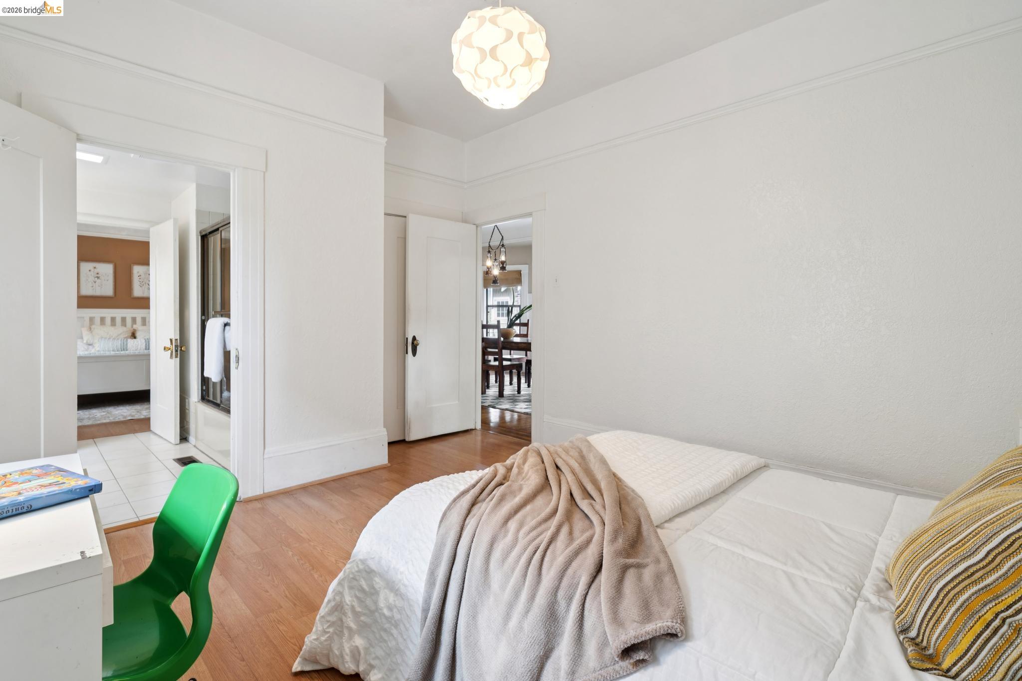892 Laurel Street Alameda, CA 94501 - Photo 29 of 45 Bedroom featuring light wood-finish flooring, a contemporary pendant light fixture, and a doorway opening to a bathroom with tile flooring and a glass-enclosed shower