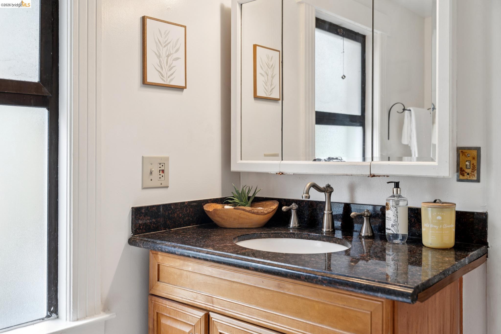 892 Laurel Street Alameda, CA 94501 - Photo 31 of 45 Vanity with a dark granite countertop, integrated sink, and an antique brass-finish faucet