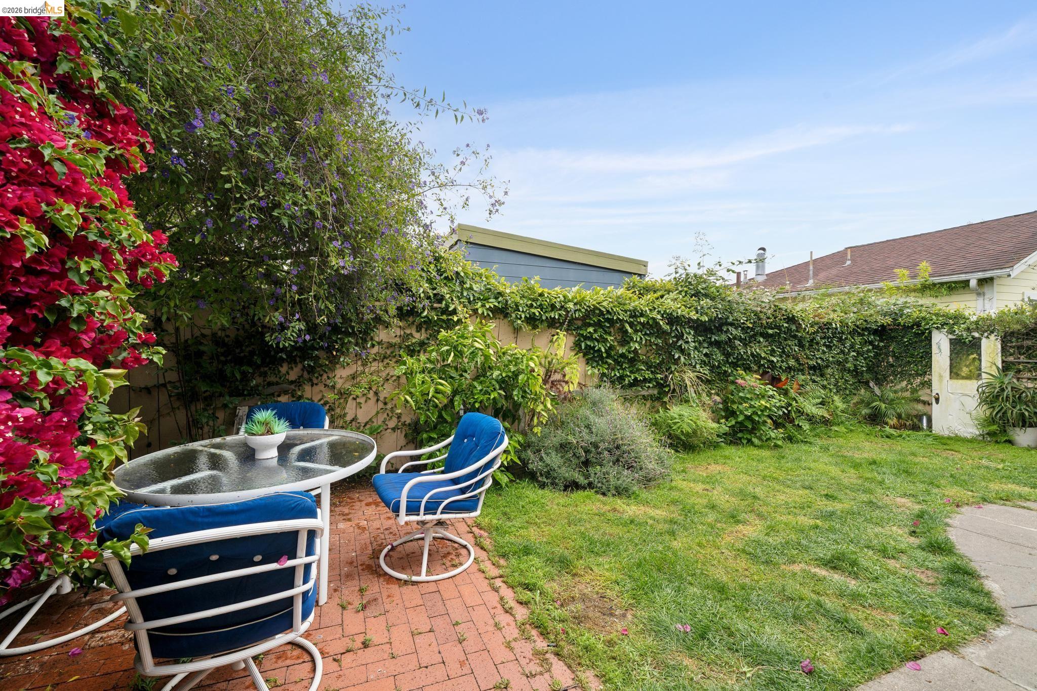 892 Laurel Street Alameda, CA 94501 - Photo 42 of 45 Outdoor patio space featuring a red brick surface, lush green lawn, mature perimeter plantings, and a climbing flowering vine