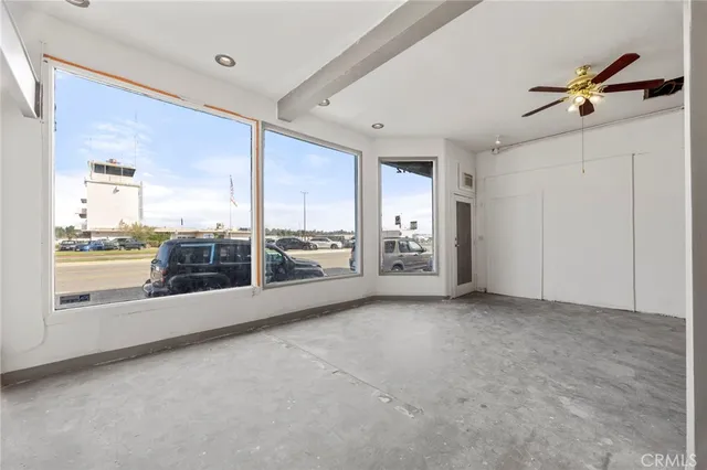 a view of a big room with windows and ceiling fan
