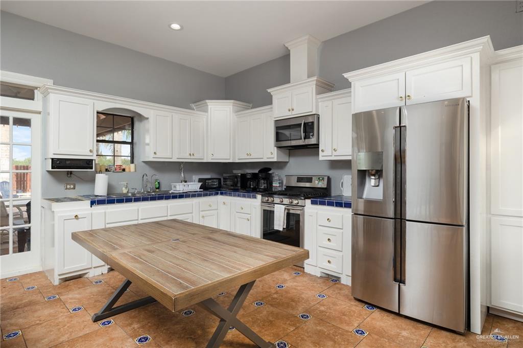 2507 East Mile 5 Road Mission, TX 78573 - Photo 20 of 34 a kitchen with a refrigerator a microwave a sink and cabinets
