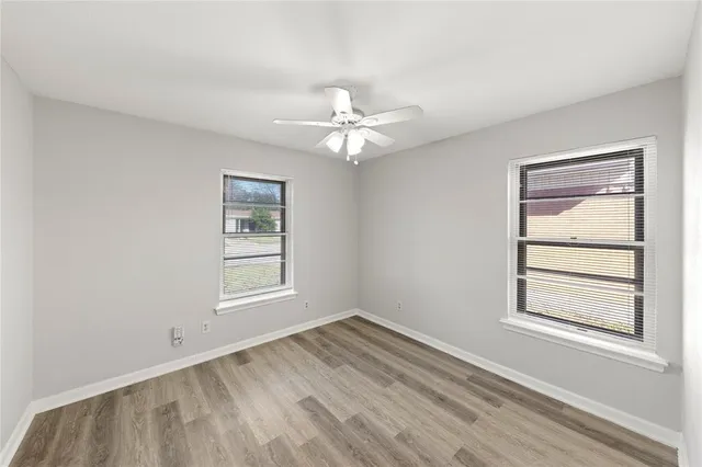 an empty room with windows and ceiling fan