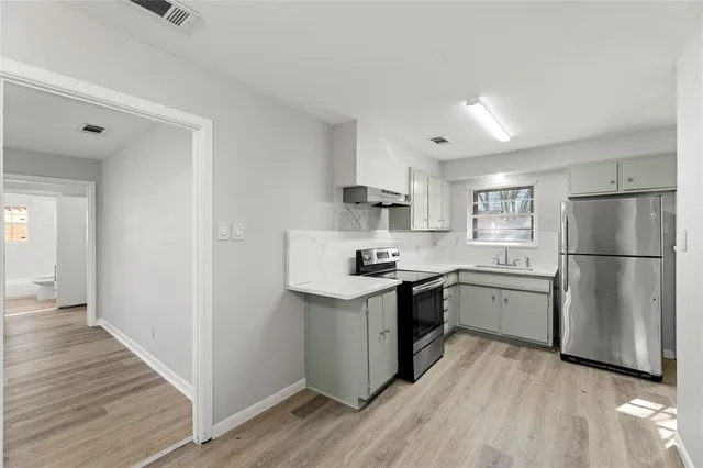 a kitchen with a sink a refrigerator and wooden floor