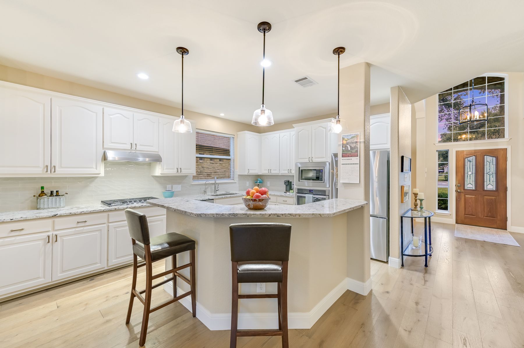 300 River Ridge Drive Georgetown, TX 78628 - Photo 11 of 32 Kitchen with decorative light fixtures, a breakfast bar, light stone countertops, white cabinetry, and a kitchen island