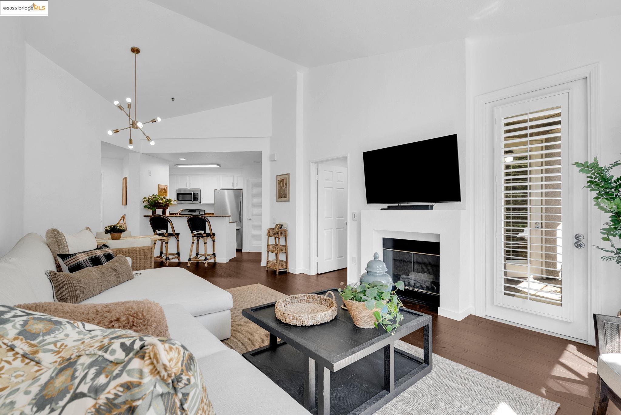 180 Caldecott Lane, Unit U314 Oakland, CA 94618 - Photo 7 of 26 Living room with dark wood-type flooring, high vaulted ceiling, a fireplace, and a chandelier
