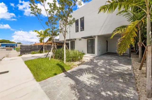 a view of a house with a yard and coconut trees