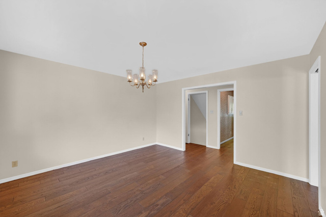 3120 North Apache Way Provo, UT 84604 - Photo 29 of 58 Spacious room featuring wood-finish flooring, a brass chandelier with glass shades, light-toned walls, and white baseboards