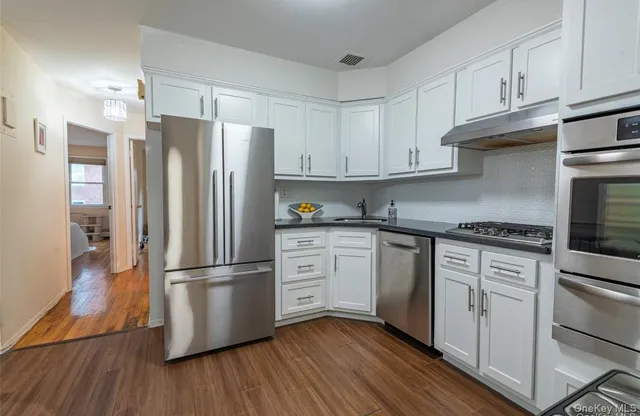 a kitchen with stainless steel appliances granite countertop a refrigerator stove and white cabinets