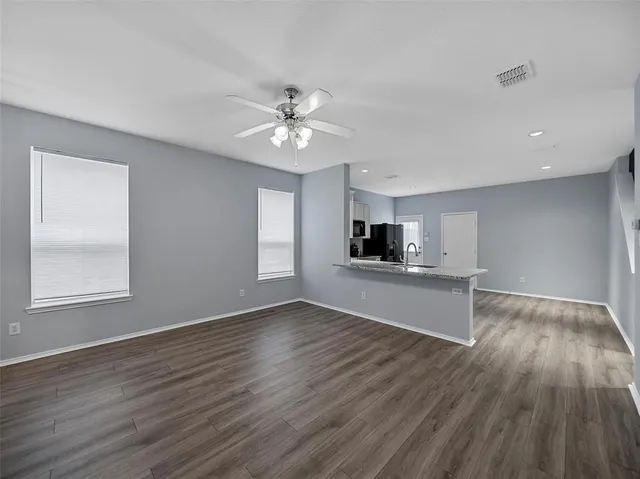 a view of a kitchen and an empty room with wooden floor and a kitchen