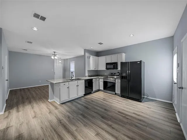 a kitchen with granite countertop a refrigerator and wooden floor