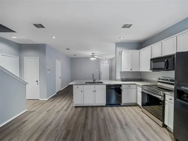 a large kitchen with granite countertop a stove top oven a sink dishwasher a dining table and chairs with wooden floor