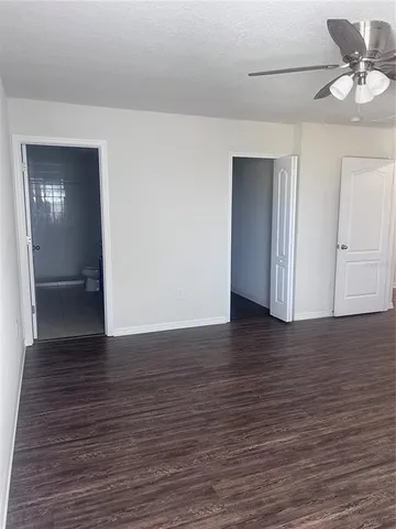 a view of an empty room with wooden floor and closet