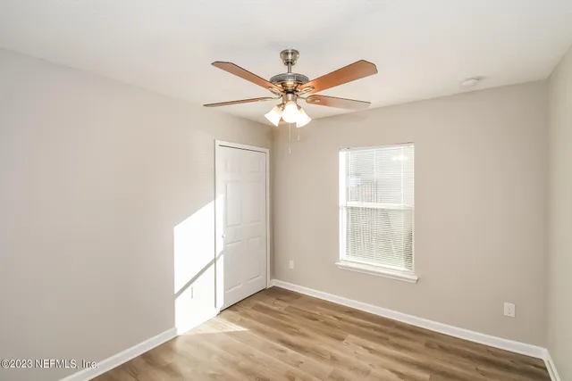 an empty room with windows and fan