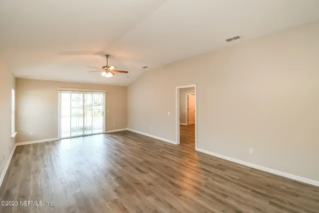 a view of an empty room with wooden floor and a window