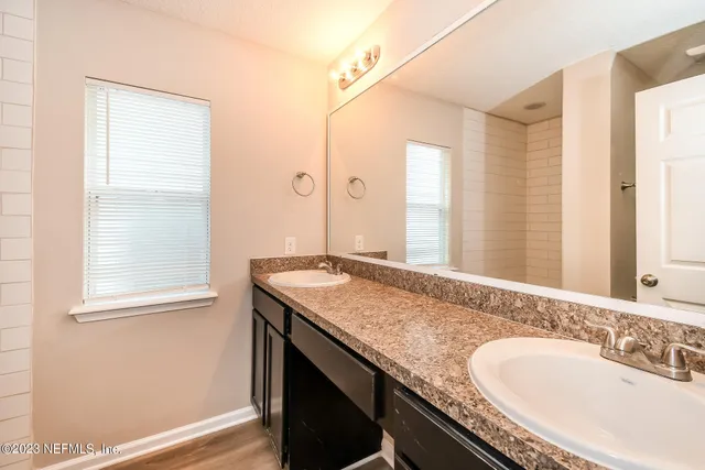 a bathroom with a granite countertop sink a mirror and a shower