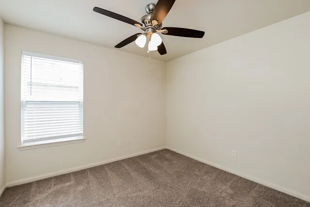 an empty room with a window and a fan