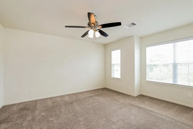 an empty room with a window and a fan