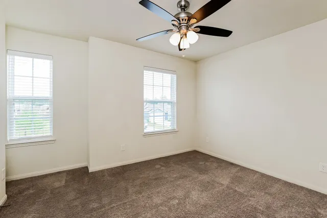 an empty room with windows and fan