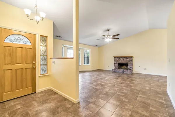 an empty room with a fireplace and chandelier fan