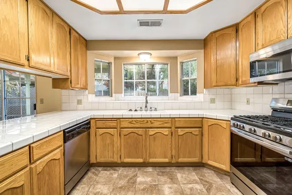 a kitchen with stainless steel appliances granite countertop a sink stove and cabinets