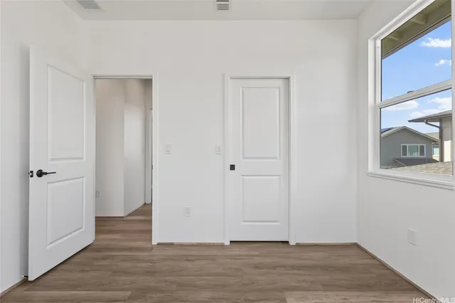 a view of an empty room with wooden floor and closet