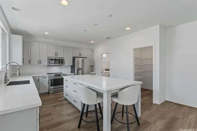 a kitchen with stainless steel appliances a table chairs refrigerator and cabinets