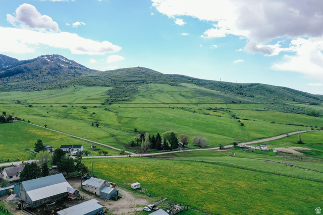 6746 North Capitol Hill Road Preston, ID 83263 - Photo 18 of 18 Expansive green landscape with distant mountains, multiple outbuildings, and a single-story residence