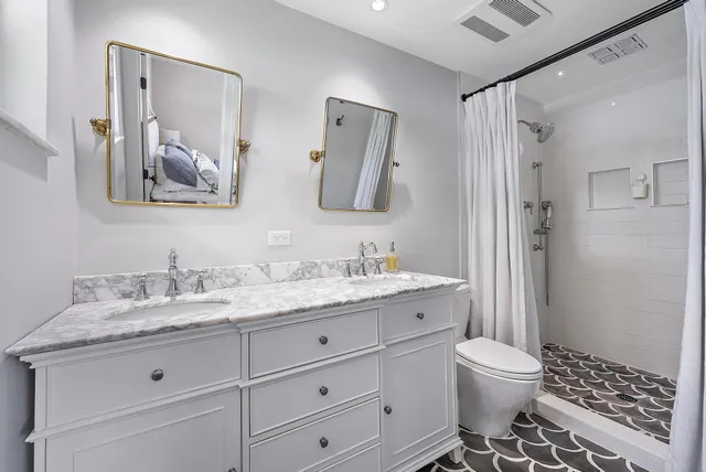 a bathroom with a granite countertop sink mirror vanity and toilet