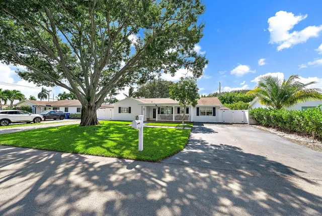 a front view of a house with a garden and trees