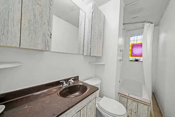 a bathroom with a granite countertop sink and a toilet