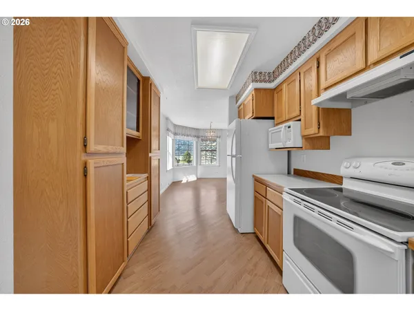 a kitchen with stainless steel appliances granite countertop a refrigerator a stove and a sink with wooden cabinets