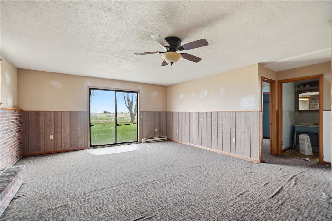 9750 Middlepoint Road Middle Point, OH 45863 - Photo 28 of 43 This living room features a ceiling fan, a fireplace, and a sliding glass door to the yard.