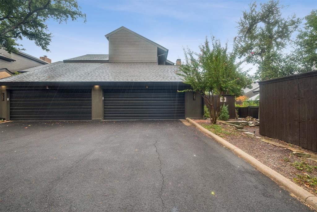 Two-car garage with black doors, exterior lighting, and a paved driveway