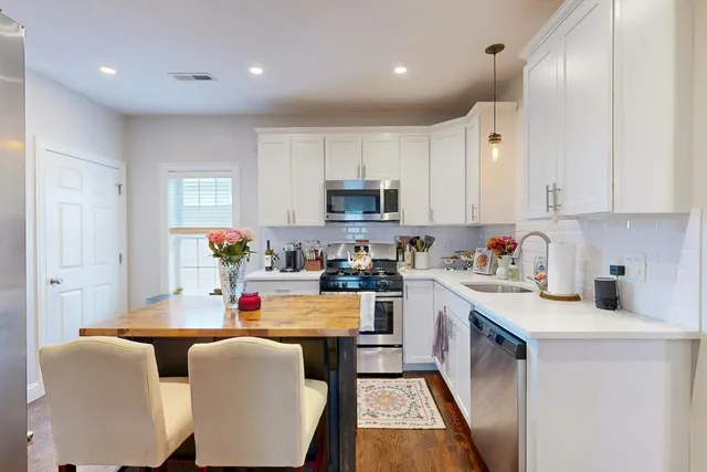 a large kitchen with stainless steel appliances granite countertop a stove a sink dishwasher and a refrigerator with wooden floor