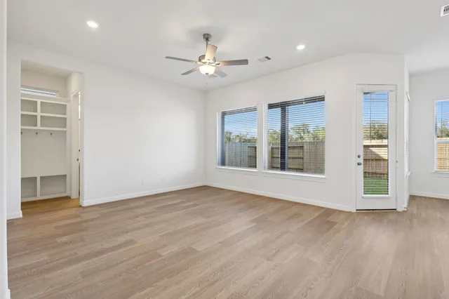 a view of an empty room with wooden floor and a window