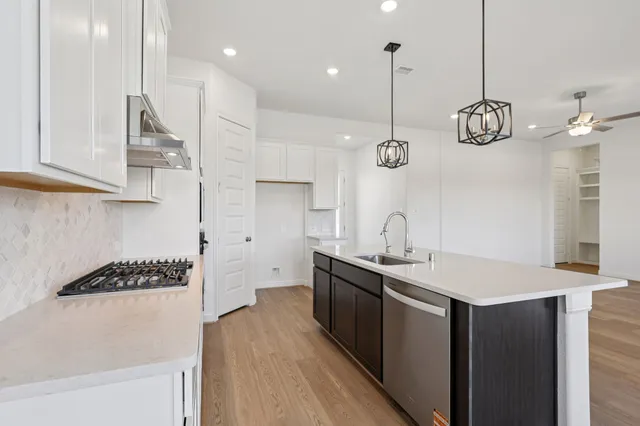 a kitchen with stainless steel appliances granite countertop a sink a stove and a wooden floors