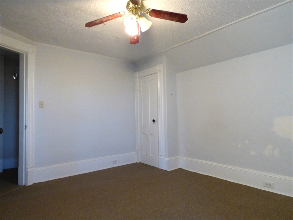298 Main Street Springfield, MA 01151 - Photo 27 of 40 an empty room with a chandelier fan and wooden floor