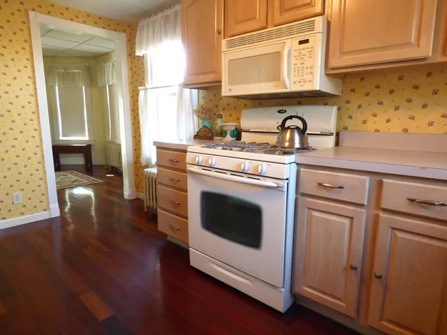 a kitchen with cabinets wooden floor and stainless steel appliances