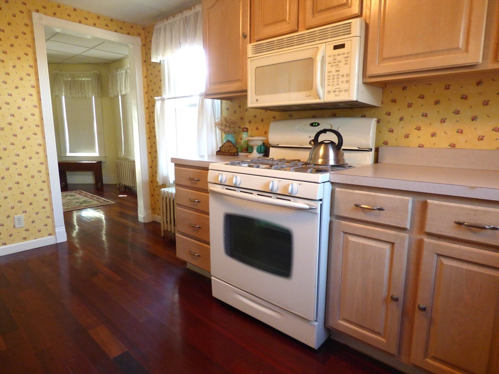 298 Main Street Springfield, MA 01151 - Photo 9 of 40 a kitchen with cabinets wooden floor and stainless steel appliances