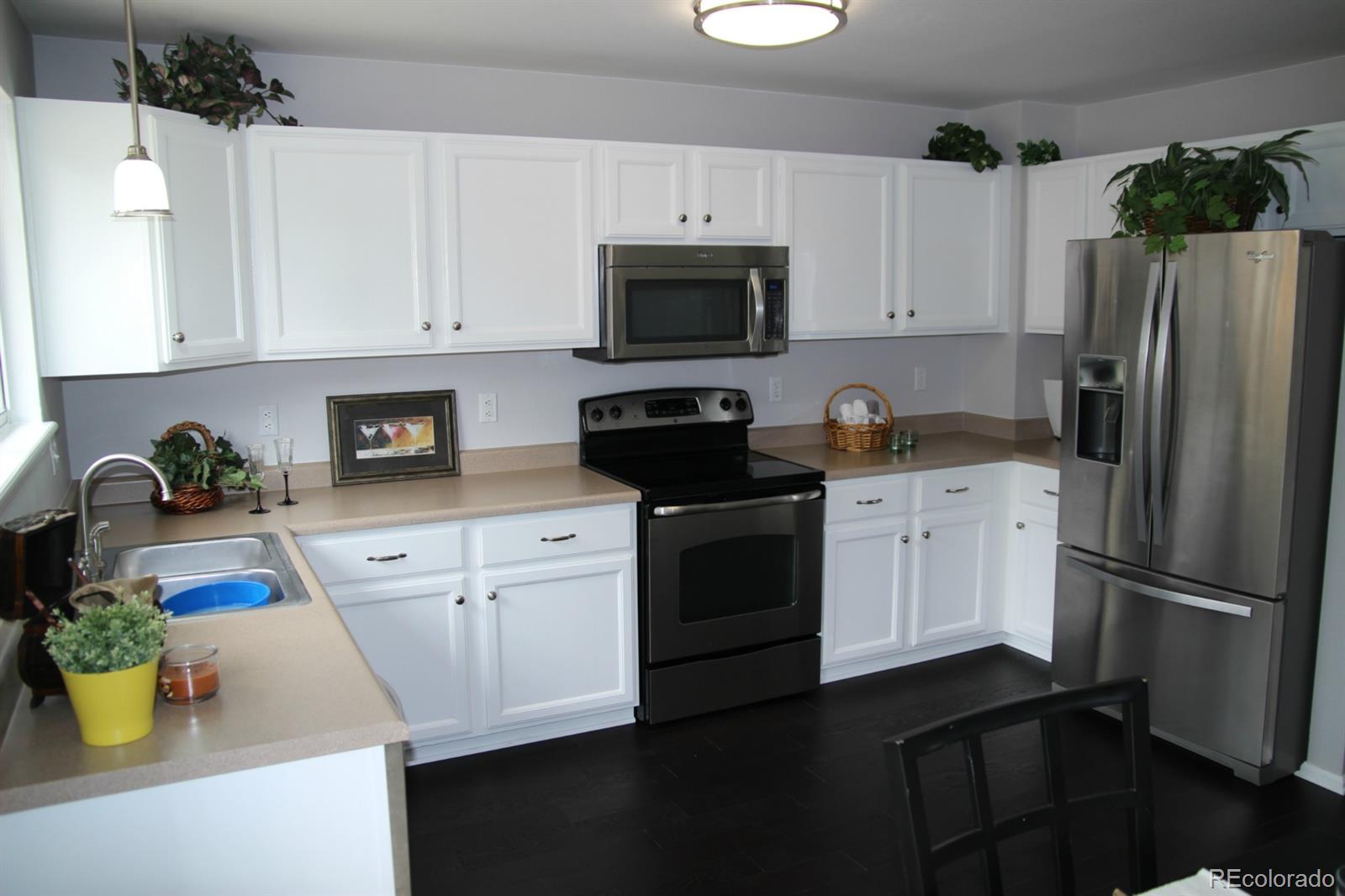 9611 South Castle Ridge Circle Highlands Ranch, CO 80129 - Photo 6 of 25 a kitchen with stainless steel appliances a white refrigerator a stove a microwave and cabinets