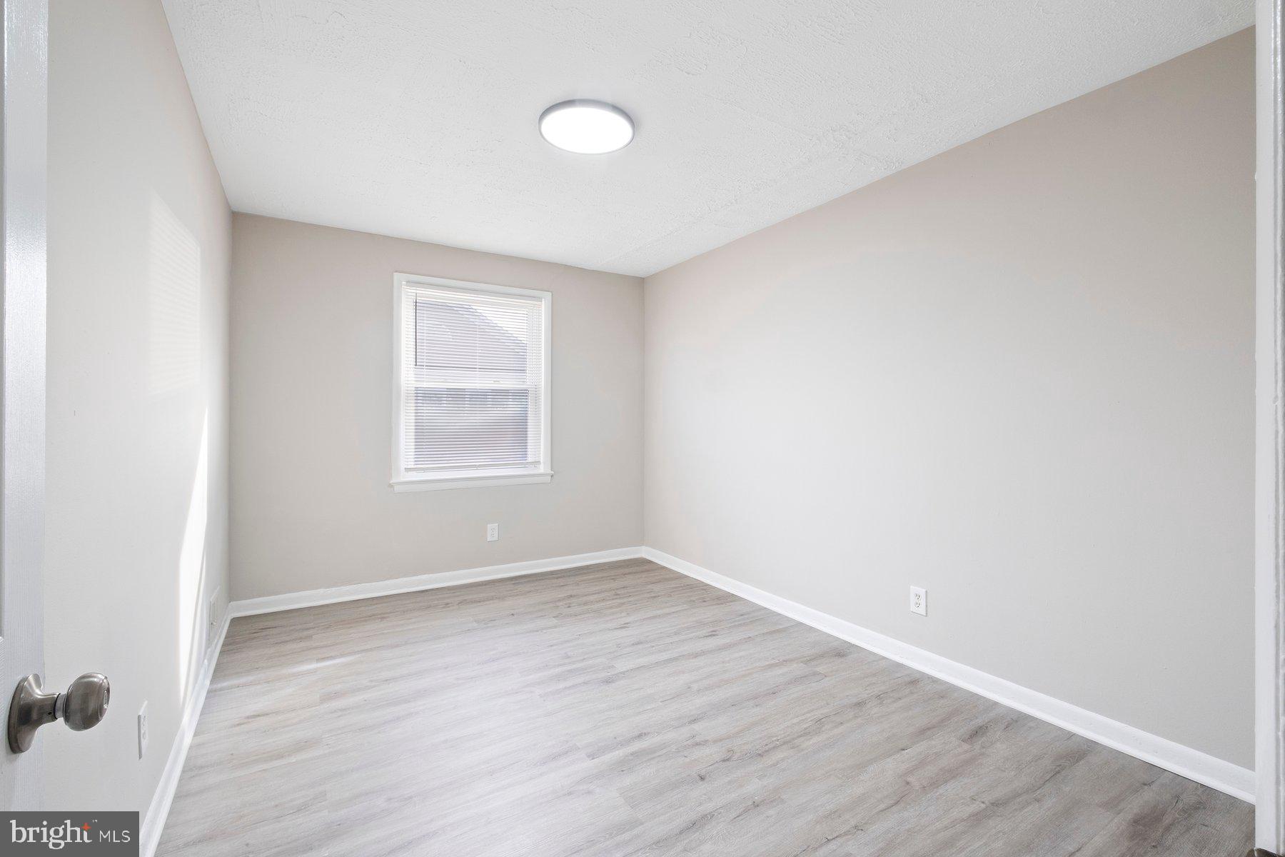 883 Bellevue Street Southeast, Unit 2 Washington, DC 20032 - Photo 12 of 37 an empty room with wooden floor and windows