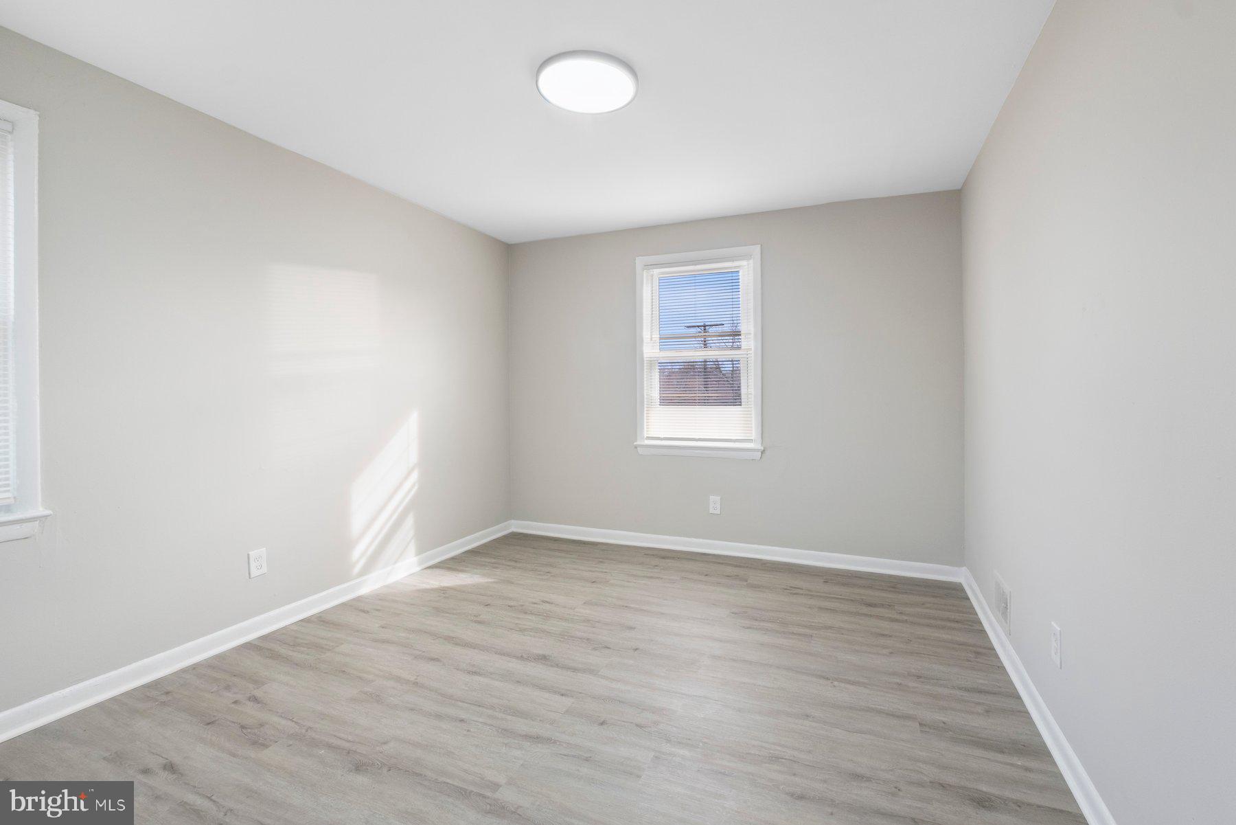 883 Bellevue Street Southeast, Unit 2 Washington, DC 20032 - Photo 14 of 37 an empty room with wooden floor and windows